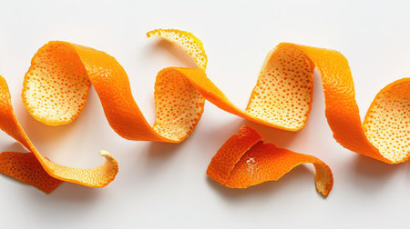Close-up of orange peel strips, arranged elegantly on a white backgroundの素材