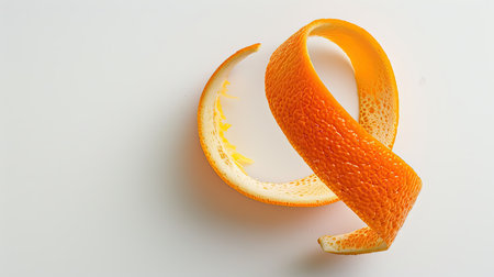 Fresh orange peel in a spiral pattern, captured against a clean white backdropの素材