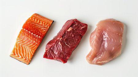 Close-up of raw salmon, chicken breast, and beef steak on a clean white background, ready for cookingの素材