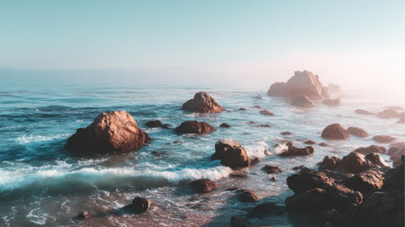 A breathtaking coastal scene featuring rocky formations rising from gentle waves, enveloped in a serene mist under a soft blue sky, ideal for calming imagery.の素材