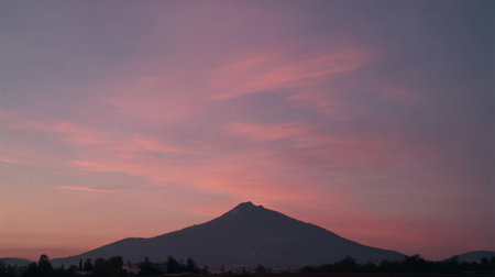 A breathtaking view of a mountain peak at sunrise, showcasing a colorful sky filled with soft clouds. This serene landscape offers a tranquil escape into natureの素材