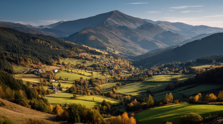 This stunning autumn landscape captures rolling hills adorned with vibrant foliage, surrounded by majestic mountains under a clear blue sky. Perfect for nature lovers.の素材