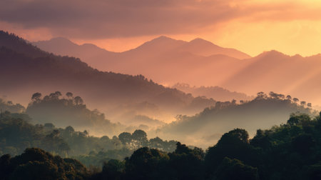 Experience the tranquil beauty of a stunning sunset illuminating rolling mountains and vibrant forests, enhanced by mist that creates a serene atmosphere.の素材