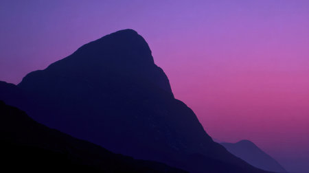 A breathtaking view of a mountain silhouette bathed in vibrant purple hues at sunrise. This image captures the serene beauty of nature's early morning light.の素材