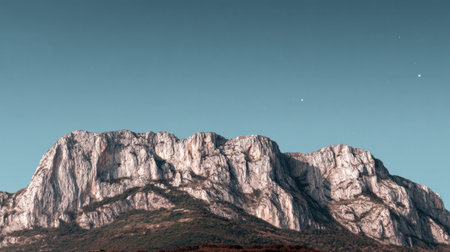 Experience the tranquility of a stunning mountain landscape featuring a textured rock face and a clear blue sky, perfect for outdoor enthusiasts and nature lovers.の素材