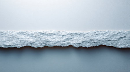 A close-up of a textured white paper edge contrasting with a smooth gray background, perfect for creative projects or design inspirations. The minimalistic look highlights natural elements.の素材
