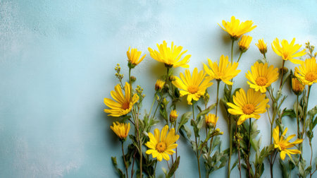 A beautiful arrangement of bright yellow flowers stands out against a soft blue background, creating a vibrant and cheerful atmosphere that evokes springtime joy.の素材