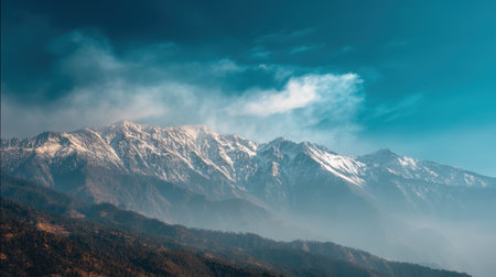 Experience the tranquility of nature with this breathtaking view of a majestic snow-capped mountain range under a bright blue sky and soft clouds.の素材