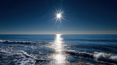 A tranquil ocean scene captures the beauty of the horizon at sunset, with bright sun rays reflecting on calm waters and gentle waves under a clear blue sky.の素材
