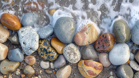 Ocean stones on sandy beach with natural wave patternsの素材