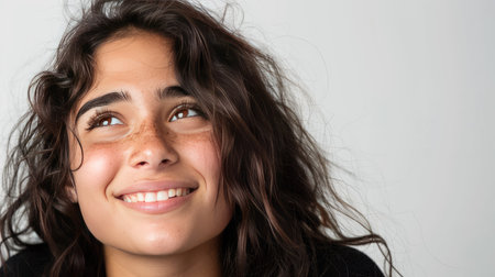 Happy brunette Latin girl with freckles, looking off to side, smiling, isolated on white background, copy spaceの素材