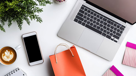 A workspace with a laptop, smartphone, and coffee cup on a white table, showing online shopping, top viewの素材