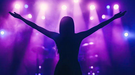Female vocalist silhouette with outstretched arms, bathed in purple and blue lights, capturing the emotion of a live performanceの素材