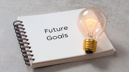 A close-up image of a light bulb next to a notebook titled 'Future Goals'. This visual symbolizes creativity, planning, and aspirations for personal growth and success.の素材