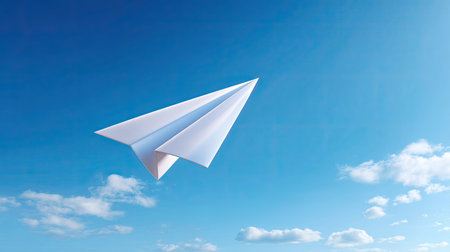 A paper airplane glides gracefully through a clear blue sky adorned with soft clouds, evoking a sense of freedom and creativity. This image captures the joy of flight and exploration.の素材