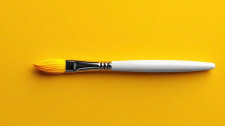 A bright yellow paintbrush rests on a vibrant yellow surface, ideal for projects related to art, creativity, and design. Perfect for inviting inspiration in any artistic endeavor.の素材