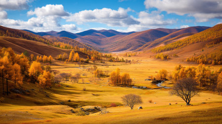 Breathtaking view of an autumn landscape featuring vibrant yellow and orange foliage in a serene valley bordered by majestic mountains and a clear blue sky.の素材