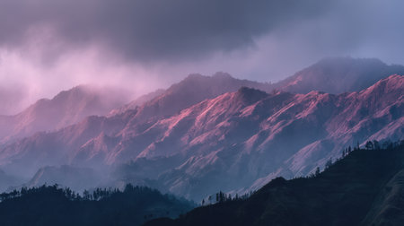 Breathtaking view of majestic mountains illuminated by soft dawn or dusk light, showcasing vibrant colors and dramatic clouds, perfect for nature lovers and adventurers.の素材