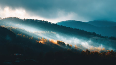 A stunning view of misty mountains at dawn, where ethereal light breaks through the clouds illuminating trees and creating a serene atmosphere perfect for outdoor enthusiasts.の素材
