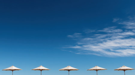 A serene beach scene featuring elegant umbrellas against a bright blue sky, creating a perfect backdrop for relaxation and summer enjoyment by the ocean coast.の素材