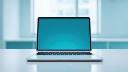 A sleek modern laptop sits on a bright office desk, showcasing a vibrant blue screen. Ideal for promoting technology, workspace, and creativity in a professional setting.の素材