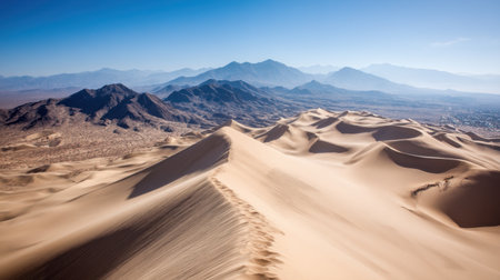 Discover the breathtaking beauty of vast sand dunes and a distant mountain range, showcasing the serene and untouched wilderness of a majestic desert landscape.の素材