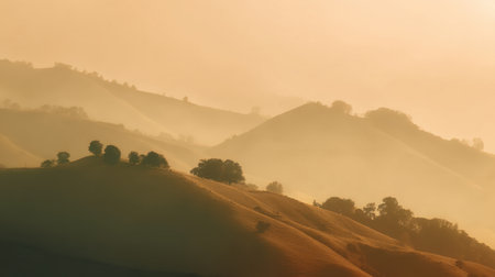 A breathtaking view of lush rolling hills bathed in morning light and gentle fog. This serene landscape captures the beauty of nature awakening at dawn.の素材