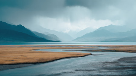 A breathtaking landscape showcases vast grasslands and majestic mountains beneath a dramatic cloudy sky, perfectly reflected in the calm water, evoking peace and tranquility.の素材