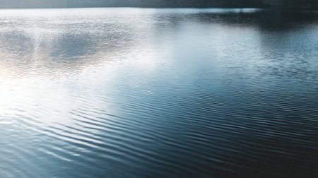 This image captures the tranquility of a calm water surface, featuring gentle ripples and reflections of the sky at dawn, perfect for evoking peace and serenity.の素材