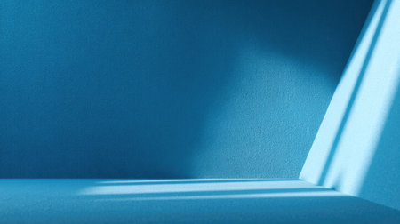 A serene blue wall and floor create a minimalist background, illuminated by soft light that casts gentle shadows, perfect for artistic and modern design projects.の素材