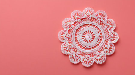 This image features a delicate lace doily set against a soft pink background, emphasizing intricate patterns and textures ideal for decoration or artistic projects.の素材