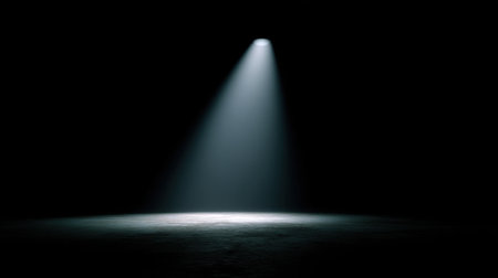 A striking spotlight pierces through complete darkness, casting light onto a bare surface below, creating an evocative atmosphere perfect for various creative projects.の素材