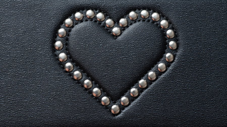 This image features a heart shape formed by silver rivets on a textured black leather background. Ideal for fashion, art, or decorative projects, the detail captures elegance.の素材