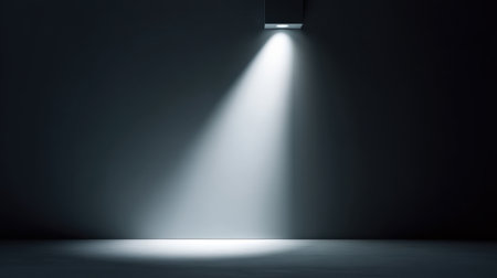 A solitary spotlight casts a soft beam into a dark room, enhancing the mood with deep shadows and creating a striking, atmospheric scene ideal for creative projects.の素材