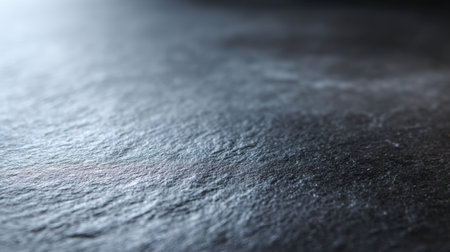 This image showcases a close-up of a textured dark surface illuminated by soft light, featuring subtle natural patterns that enhance its artistic appeal.の素材