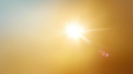 A stunning capture of bright sunlight filtering through a clear blue sky, creating warm golden tones. This image conveys a sense of peace and serenity, perfect for backgrounds.の素材