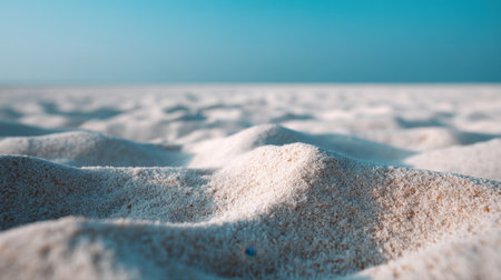 A breathtaking close-up image of soft sand dunes, showcasing the intricate textures and gentle undulations beneath a serene blue sky, perfect for evoking peace.の素材