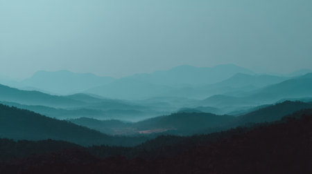 A breathtaking view of tranquil blue mountains shrouded in mist at dawn, showcasing layered silhouettes that evoke a sense of calm and serenity in nature.の素材