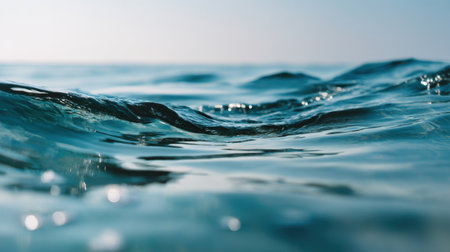 A stunning view of gentle ocean waves rolls gracefully under a bright blue sky, sparkling sunlight dances on the water surface, creating a serene coastal atmosphere.の素材