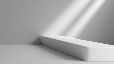 This image features a minimalist exhibit space with soft light highlighting a white rectangular object against a gray wall, perfect for artistic presentations.の素材
