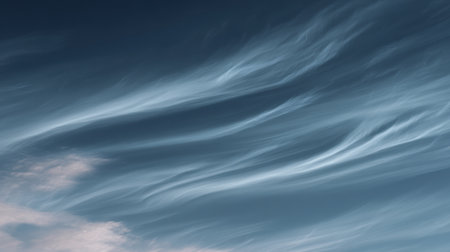 Experience the beauty of soft wispy clouds flowing through a deep blue sky, creating an ethereal atmosphere at dusk, perfect for artistic and serene projects.の素材