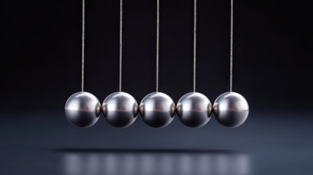 This striking image features a Newton cradle with metallic spheres in motion, embodying principles of physics such as energy transfer and momentum. Perfect for educational use.の素材
