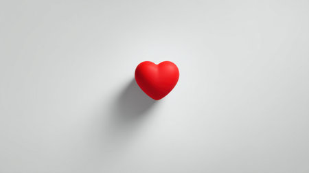 A vibrant red heart shape rests on a smooth, minimalist white background, conveying a sense of love and emotion perfect for a variety of creative and romantic projects.の素材
