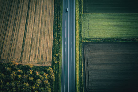 Rural highway running through farmland, a few cars driving through the peaceful countrysideの素材