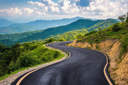 A winding asphalt road through the mountains, with sharp turns and elevation changes, offering a thrilling drive with scenic views.の素材
