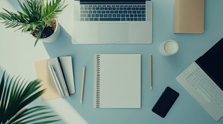 an organized desk from a top view, with neatly arranged stationery, a notebook, a laptop, and a plant in the corner.の素材
