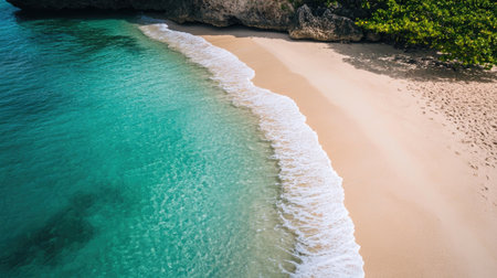 an empty beach from a top view, with untouched sand and clear, tranquil waters gently lapping at the shore.の素材