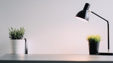 A modern desk setup featuring a sleek black lamp and two decorative plants. The minimalist design creates a bright and inviting workspace atmosphere.の素材