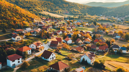 A picturesque autumn village nestled in a scenic mountain landscape, showcasing charming houses surrounded by vibrant trees and peaceful countryside views.の素材