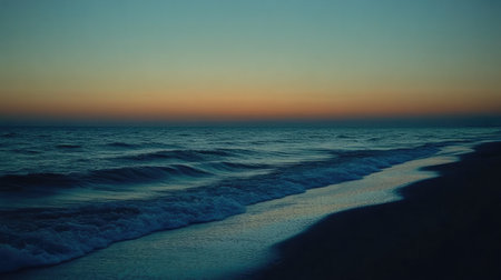 A serene view of gentle ocean waves lapping against the shore as the sun sets, casting beautiful hues across the sky, perfect for relaxation and escape.の素材